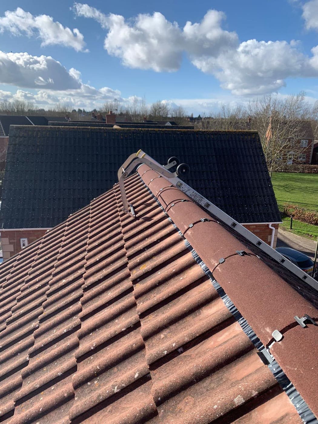 Dry ridge system fitted along a red concrete tiled roof, with the roof ladder in place